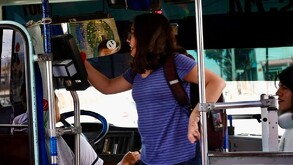 Se observa a una joven subiendo un camión y se observa un hombre sentado manejando.