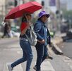 Dos personas caminan por las calles de la capital utilizando una sombrilla para protegerse del sol.