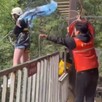 A la izquierda: Una mujer con una bandera en una tirolesa y un trabajador detrás sosteniendo una cuerda. A la derecha: la misma mujer cayendo de la tirolesa