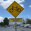 Se observa un letrero color amarillo que dice ciclovía, atrás está la calle.