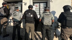 Se observa a varias personas de espalda y están esposados.