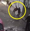 Personas en la vía pública agitando lanzando piedras hacia la parte alta de un edificio.