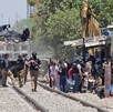 Policías de la Fiscalía de Jalisco durante operativo en Pueblo Quieto con personas, casas, maquinaria pesada alrededor de unas vías del tren