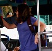 Se observa a una joven subiendo un camión y se observa un hombre sentado manejando.