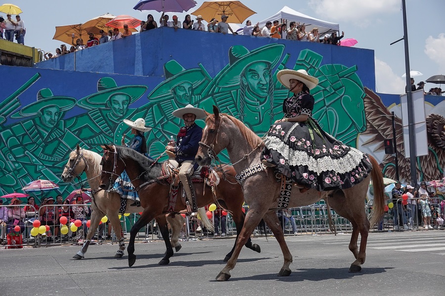 Personas montadas a caballo avanzan sobre una calle de Puebla.