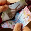 Manos de una persona abriendo una cartera con billetes mexicanos de distinta denominación