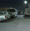 Se observa que es de noche, hay unos autos estacionados en la vía pública.