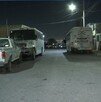 Se observa que es de noche, hay unos autos estacionados en la vía pública.