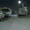 Se observa que es de noche, hay unos autos estacionados en la vía pública.