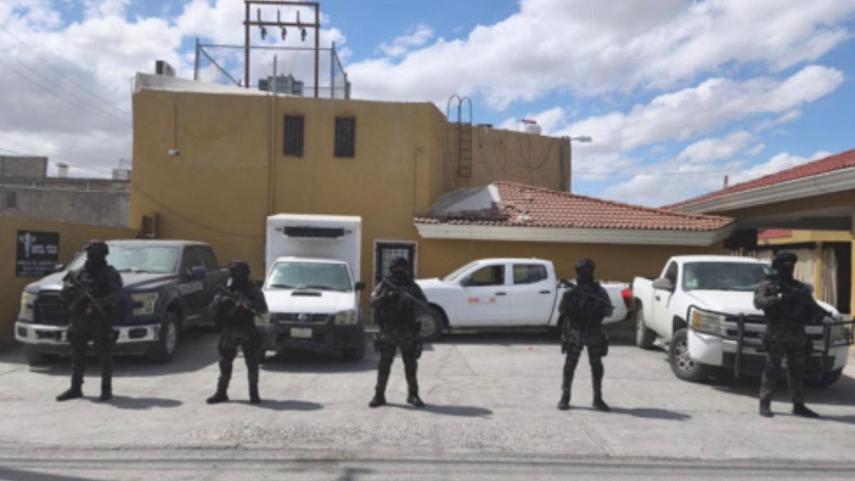 Policías con uniforme negro frente a varias camionetas