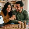 Una pareja en una sal frente a una laptop con gráficas y varias columnas de monedas