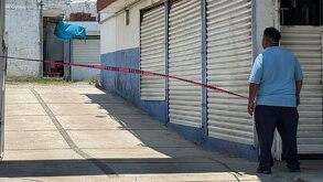 Hombre se asoma a un pasillo del Mercado Morelos después de una balacera.