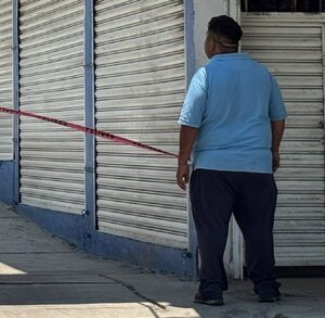 Hombre se asoma a un pasillo del Mercado Morelos después de una balacera.