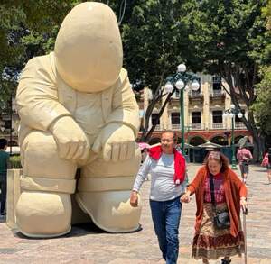 Escultura artística en el Zócalo de Puebla con personas caminando junto a ella