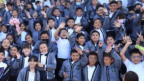 niños con uniforme escolar sonriendo y saludando a la cámara en una foto grupal
