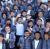 niños con uniforme escolar sonriendo y saludando a la cámara en una foto grupal
