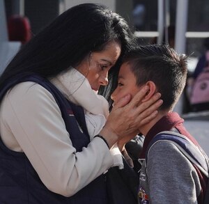 Mujer besa a su hijo antes de dejarlo en la escuela.