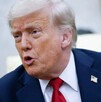 Donald Trump interactuando con alguien. El presidente habla mientras porta un traje azul con un pin de la bandera de los Estados Unidos.