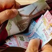 Manos de una persona abriendo una cartera con billetes mexicanos de distinta denominación