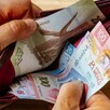 Manos de una persona abriendo una cartera con billetes mexicanos de distinta denominación