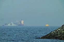 Una patrullera emiratí (izquieda), navega cerca de un petrolero fondeado en el golfo de Omán, cerca del estrecho de Ormuz