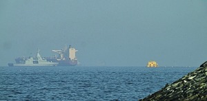 Una patrullera emiratí (izquieda), navega cerca de un petrolero fondeado en el golfo de Omán, cerca del estrecho de Ormuz