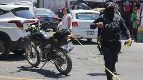 Policía coloca cinta de seguridad junto a una motocicleta.