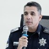 Hombre vestido con uniforme policiaco hablando ante un micrófono.