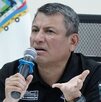 Hombre serio hablando ante un micrófono con la mano estirada.