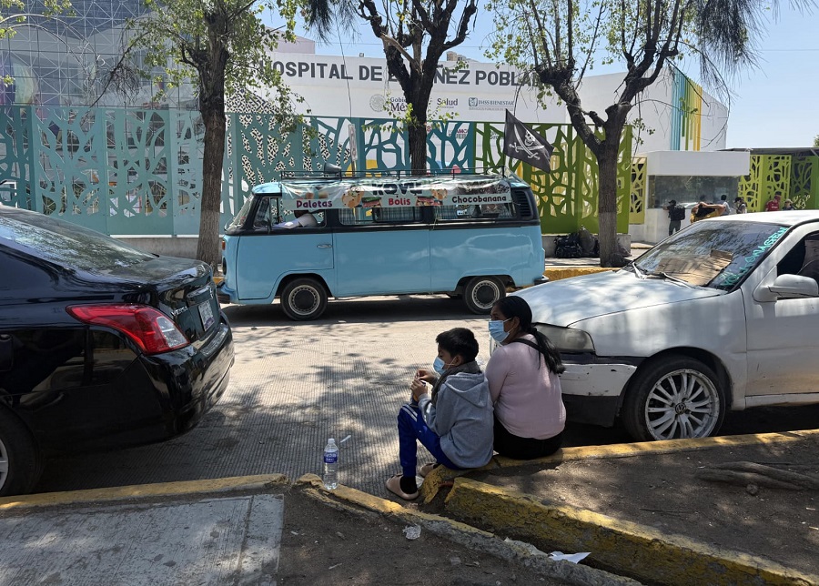 Mujer y niño usan cubrebocas afuera de un hospital.