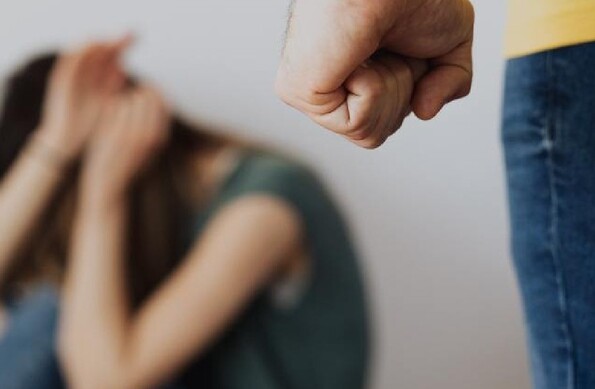 Puño de hombre amenazando a mujer que se cubre el rostro