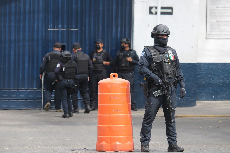Policía armado parado frente a una corporación.