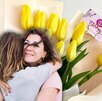 Mujer abraza a otra mujer con un fondo floral.