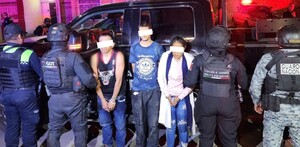 Dos hombres y una mujer con los ojos censurados y esposas en las manos siendo detenidos por agentes de la Secretaría de Seguridad Jalisco
