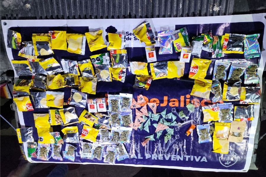 paquetes de distintas drogas envueltos en bolsas de sabritas sobre una manta de la Secretaría de Seguridad Jalisco