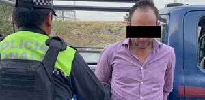 Hombre con los ojos censurados por un recuadro negro siendo detenido por un oficial de la Policía de Tonalá con una patrulla detrás
