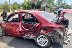 Automóvil color rojo destrozado de la puerta trasera y la cajuela en medio de una carretera de Tala con un policía enfrente