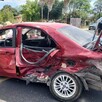 Automóvil color rojo destrozado de la puerta trasera y la cajuela en medio de una carretera de Tala con un policía enfrente