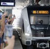 usuarios en una estación del tren ligero, tomando video mientras lo esperan