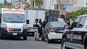 Policía de Guadalajara con militares de la Guardia Nacional enfrente de un auto con una patrulla y una ambulancia de la Cruz Verde alrededor