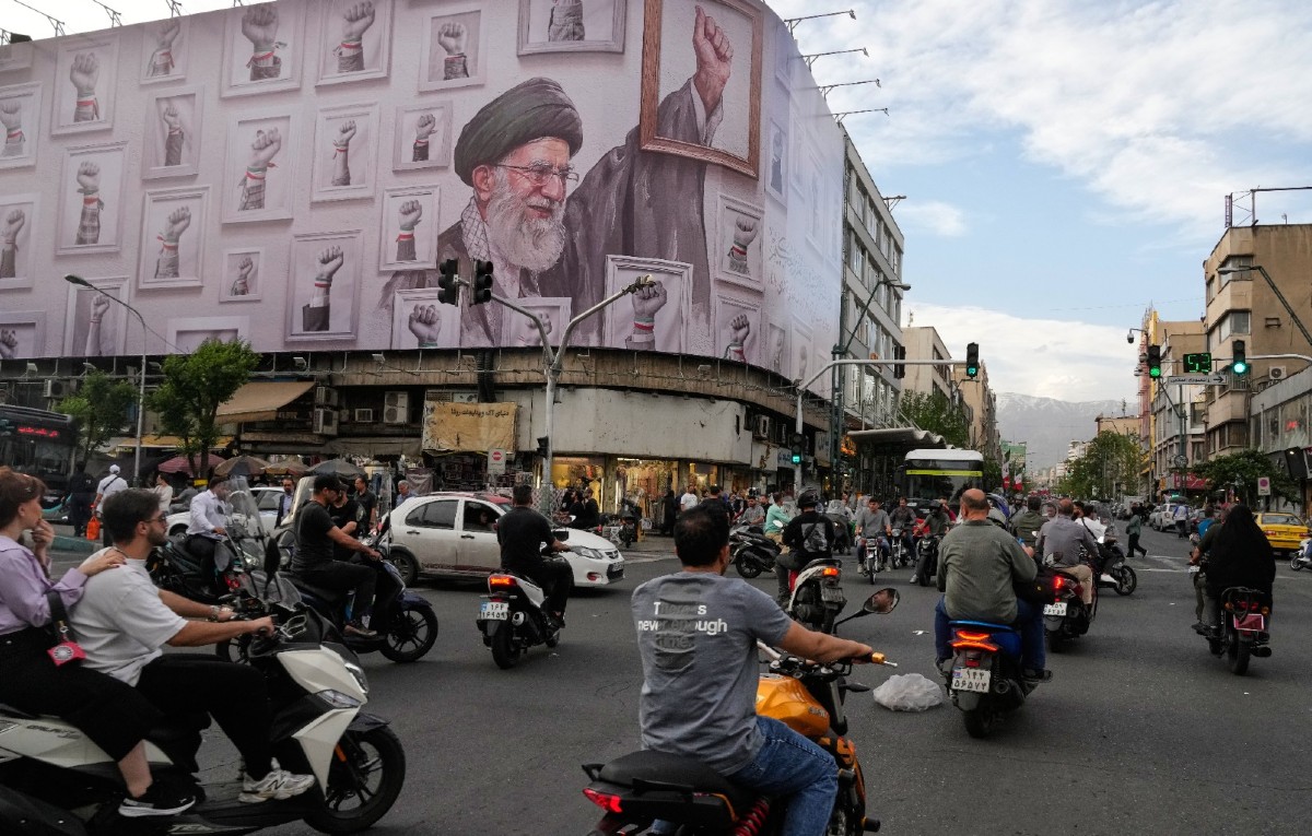 Motocicletas pasan ante un cartel que muestra una imagen del fallecido líder supremo de irán, el ayatolá Alí Jamenei, fallecido en ataques de Estados Unidos.