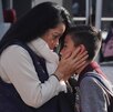 Mujer besa a su hijo antes de dejarlo en la escuela.