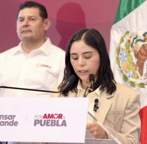 Mujer de camisa blanca leyendo un documento junto al gobernador de Puebla, Alejandro Armenta.