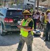 Se observa a varias personas y a un niño que lo están cargando en brazos, hay unas camionetas.