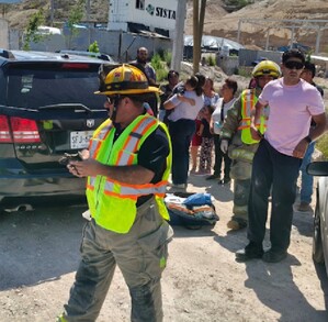 Se observa a varias personas y a un niño que lo están cargando en brazos, hay unas camionetas.
