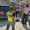 Se observa a varias personas y a un niño que lo están cargando en brazos, hay unas camionetas.