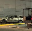 Se observa un carro color gris destruido  y una patrulla a un lado; es de noche.