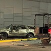 Se observa un carro color gris destruido  y una patrulla a un lado; es de noche.