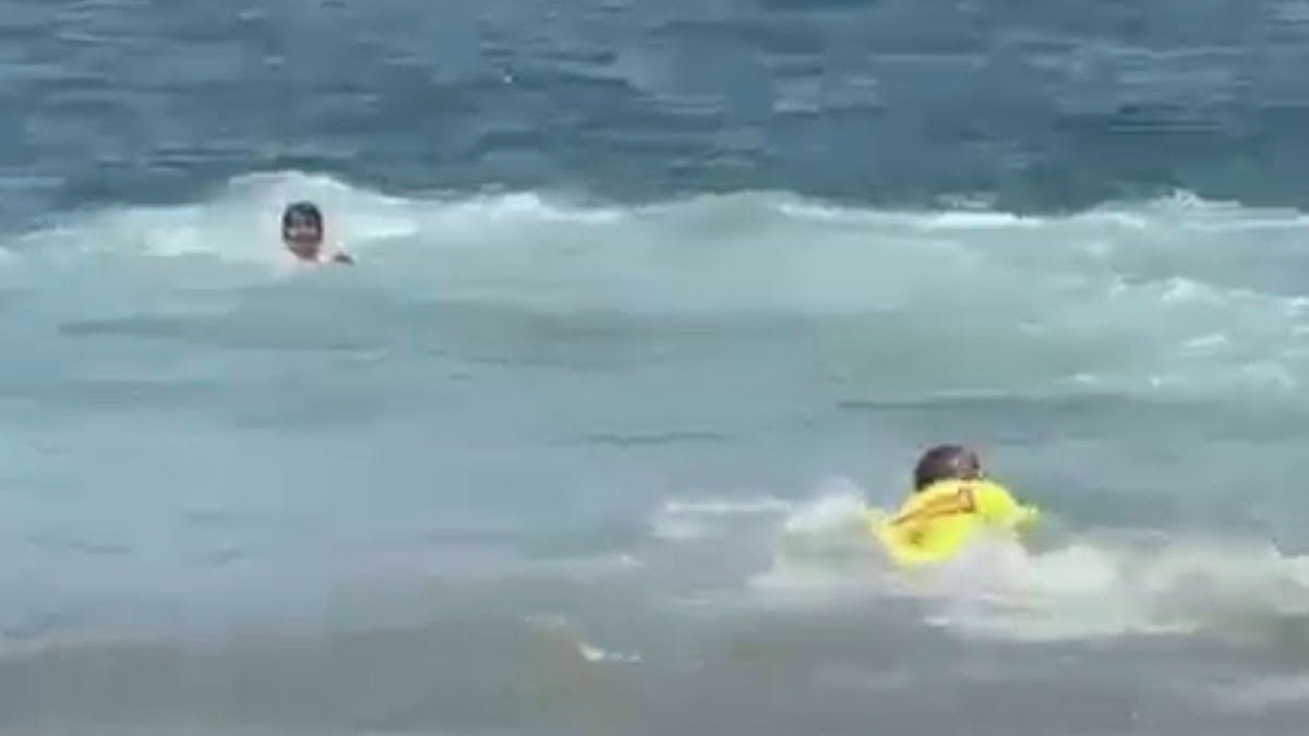 Guardavidas nadando en el mar de Playa La Audiencia para rescatar a una mujer atrapada por el fuerte oleaje
