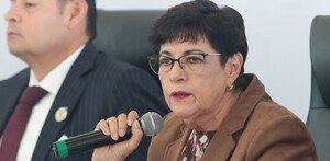 Mujer de lentes y edad avanzada hablando con un micrófono en la mano.